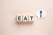© Fahad - Minimalist wooden blocks spelling EAT, healthy nutrition concept with fork icon, clean diet and meal planning background