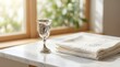 © Jhon - Silver kiddush cup and folded embroidered white napkin on a white marble table