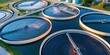 © Georgii - Aerial view of circular water treatment tanks with rippling blue water and industrial equipment at golden hour