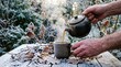 © pattaphorn - Person Pouring Hot Tea from Kettle into Cup in Frosty Autumn Garden with Beautiful Scenery