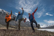 © ANDREY - Low angle front view of a group of mature senior backpackers cheering and kicking legs on a mountain trail, active aging concept