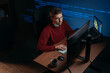 © Arsenii - Software engineer wearing eyeglasses working at multi-screen desk in a dark office, focused on code and graphs. Programmer works late at night on a demanding data science and AI task. Copy space