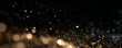 © IvanLi - Gold dust particles scatter in a dark space. The tiny specks glow with soft warm light and varying intensity. This image captures a sparkling bokeh effect perfect for festive or background.