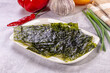 © Andrei Starostin - Crispy nori seaweed sheets on white plate with red pepper, garlic, and green onions in soft natural light