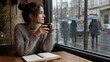 © Yuliia Yevdokymova - Woman Holding Coffee by Rainy Window in Cozy Urban Cafe Interior
