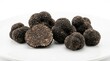 © M Qamar - Fresh black truffles displayed on a white plate showcasing their textured earthy exterior with luxury food rare mushrooms edible fungi cooking ingredient truffles mushroom gourmet food delicacy