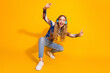 © deagreez - Young girl with blue headphones jumps and poses with thumbs up against a bright yellow background for a fun upbeat fashion music leisure lifestyle image