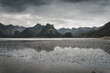 © Travel 'n' Lifestyle - View of the rugged mountains along Midnattsolveien reflected in the tidal flats under a dramatic cloudy sky in Laukvik, Nordland, Norway.