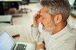 © Davor - Stressed mature man with headache at office desk using laptop