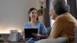 © Father_Studio - Portrait of friendly Asian female nurse smiling and discussing health care treatment with senior couple, sitting in living room during home medical consultation.