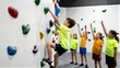 © joeycheung - Children climb colorful indoor rock wall while peers cheer from below.