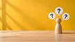 © Rohani - Wooden figure with three speech bubbles containing question marks symbolizing confusion or inquiry against a yellow textured background