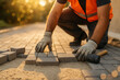 © thodonal - Worker laying rectangular paving blocks beside a rubber mallet