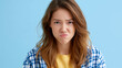 © GrayFrog - Portrait of a young woman with a sulking and annoyed facial expression against blue background.