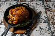 © Stacy Howell - Rotisserie chicken in a cast iron skillet with herbs and a carving knife