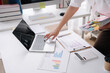 © Kritdanai - Overworked Office Life: A busy person's desk is piled high with documents and a laptop, reflecting the demanding nature of modern work.