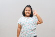 © ArvStd - Smiling Asian schoolgirl showing an OK hand gesture isolated on gray background.