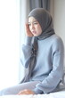© unikyluckk - Young Muslim woman suffering from severe headache at home. Asian woman wearing hijab touching her painful temples on bed. Hijabi girl feeling discomfort and migraine symptoms in bedroom.
