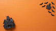 © designboundary - A black haunted house and scattered bats sit on a vivid orange surface for Halloween season