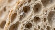 © Nazri - Extreme close-up macro shot of artisanal sourdough bread crumb texture showing large open air bubbles or alveoli, gluten network structure, and porous interior of freshly baked rustic loaf.