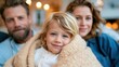 © Pinklife - A joyful family with a child snuggled together under a blanket, radiating warmth and love in a cozy setting with soft lights in the background, sharing a precious moment.
