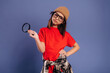 © standret - Young girl wearing red t-shirt and glasses holds magnifying glass, dressed in casual attire with plaid shirt tied around waist against a blue background