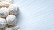 © svastix - A collection of soft white wool yarn balls laid out against a smooth background, ideal for knitting and crochet enthusiasts looking for inspiration.