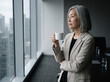 © Lorian - East Asian executive in her 60s pausing at a boardroom window