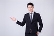 © ChauBich - Confident Asian Businessman in Suit Presenting with Open Hand Gesture