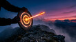 © Maksym - Archer aims glowing arrow at target on mountain peak at sunset