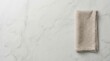 © Zaiseefa - Light gray marble table surface with a folded beige linen napkin and minimalist top down view.