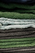 © Tina - Vertical macro close up view of a neat stack of folded colorful cotton terry towels in green grey and blue shades showing detailed soft textile loop texture and fabric layers