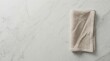 © Panpatsa - Natural material texture background featuring a folded beige linen napkin on a light gray marble table surface.