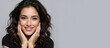 © NeuroCake - Studio portrait of smiling woman with wavy brunette hair touching jaw on grey background