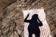© Cara Dolan/Stocksy - Summer vacation shadow selfie with rock and beach towel