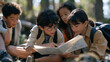 © AnastasiiaRozhmanova - An interracial group of children in outdoor woodland surroundings reading a printing press manual together, a hand bell sitting unrung nearby, one child with round glasses tracing