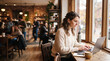 © Thumbs - Woman working on a laptop in a cozy cafe by the window
