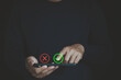 © MUNTHITA - Businessman using a smartphone with green check and red cross icons, illustrating digital decision making, approval, rejection, verification, quality control, and online business evaluation.