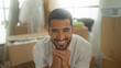 © Krakenimages.com - Man smiling during moving, surrounded by cardboard boxes with clasped hands in a building; joy new home.