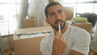 © Krakenimages.com - Man holds pen to chin amid stacked cardboard moving boxes and packing materials in building with sunlit windows; thoughtful planning.