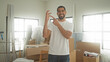 © Krakenimages.com - Man holding keys and pointing finger at key amid packed cardboard boxes and moving supplies in building; new home pride.