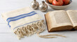 © Vendi - Jewish Rosh Hashanah concept with tallit prayer shawl, open Torah book, and pomegranates on wooden background.