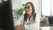 © Krakenimages.com - Woman doctor adjusts headset while typing at a computer with stethoscope in a building; telemedicine calm professionalism.