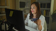 © Krakenimages.com - Woman holding creditcard in hand and typing at computer screen inside a building at night, smiling while leaning forward; online shopping confidence.