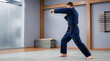 © Setiadi - Focused martial artist in blue uniform practicing karate punches inside a modern training dojo