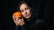 © Света Шелест - Young adult white woman holds a small glowing carved pumpkin against her cheek Halloween