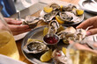 © New Africa - Women eating delicious oysters at wooden table, closeup