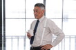 © ultramansk - Coffee break with senior Asian businessman at office near window with blinds in a modern office, medium shot, Asia, office work routine, small business and startup