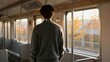 © Leon - A young man stands inside a moving train, gazing out at golden autumn foliage passing by during sunset.