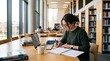 © Alensana - Focused female college student studying and writing notes in university library